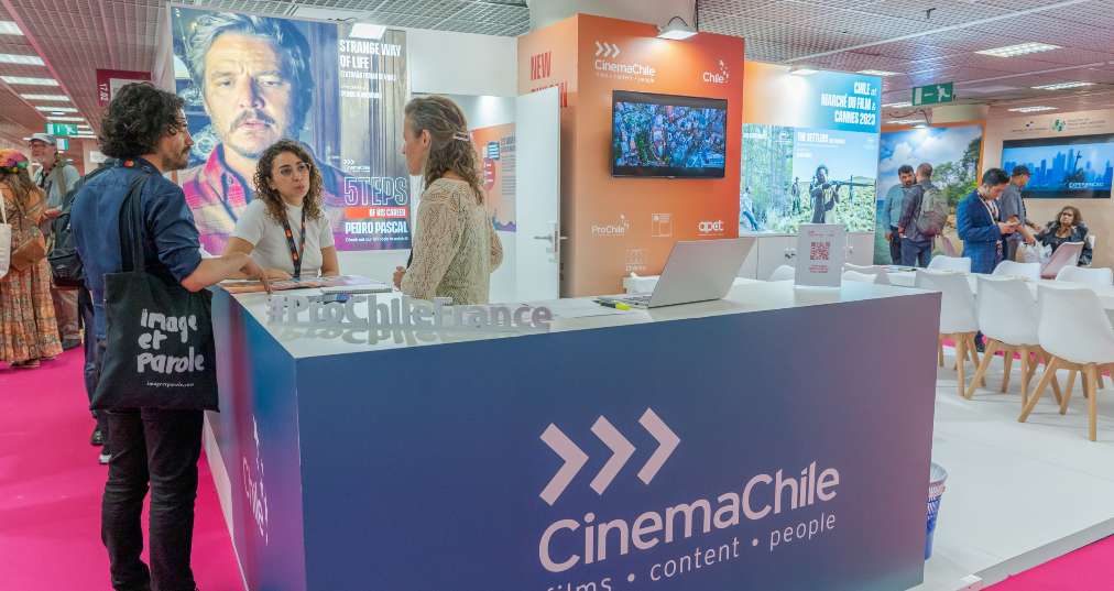 Dos mujeres y un hombre conversan en el stand de Chile en Marché du Film 2023 en el Festival de Cine de Cannes