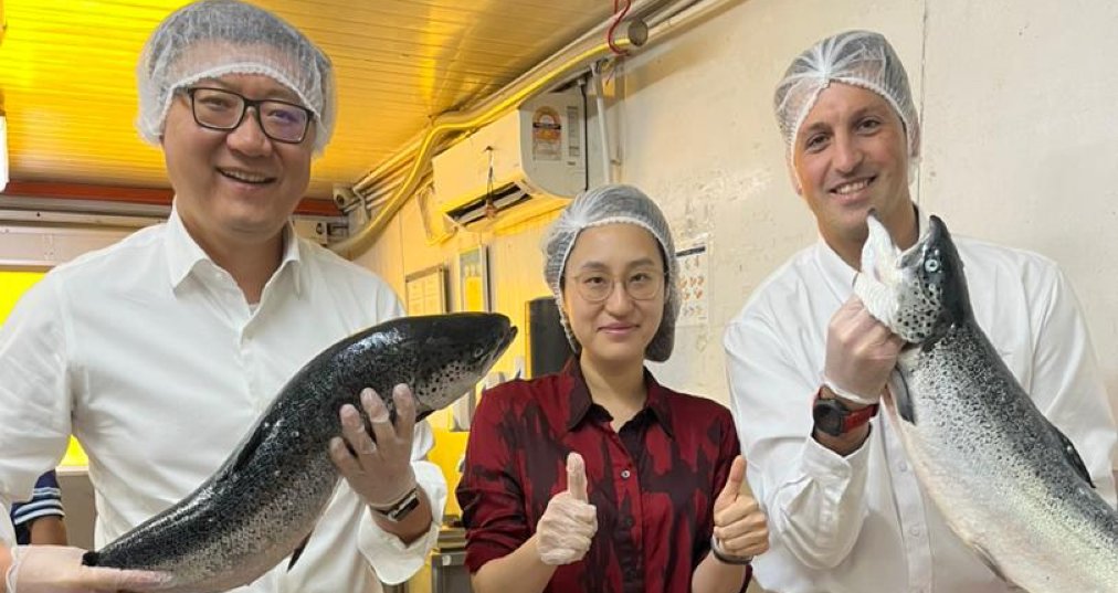 Tres personas sostienen un salmón chileno en Malasia